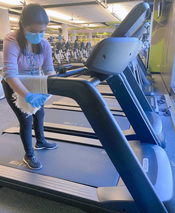 A Lincoln Park High School student cleans a treadmill during her shift.