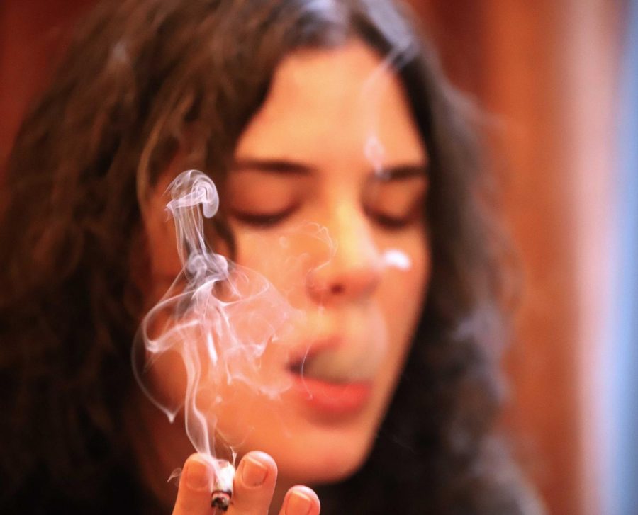 Senior Caroline Sands exhales smoke from a rolled joint to test out the joint paper.