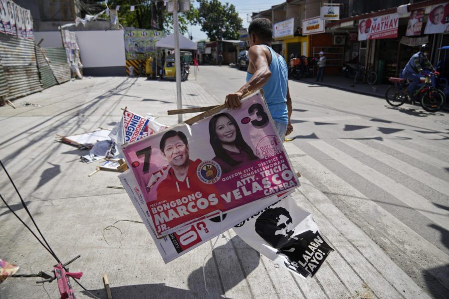 A village worker removes a campaign poster showing Presidential candidate Ferdinand “Bongbong” Marcos Jr., left, along a street in Quezon city, Philippines on Wednesday, May 11, 2022. Marcos is the son of longtime dictator Ferdinand Marcos, who died in 1989. (Aaron Favila | AP)
