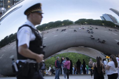 A Chicago police officer walks by the Bean in Millennium Park Thursday afternoon as visitors take photos near the attraction.