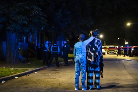 Family members watch as Chicago police investigate in the 5700 block of South Carpenter Street, where a man was shot to death during a party on the Englewood neighborhood block on the South Side, early Sunday, May 29, 2022, in Chicago. (Ashlee Rezin/Chicago Sun-Times via AP)