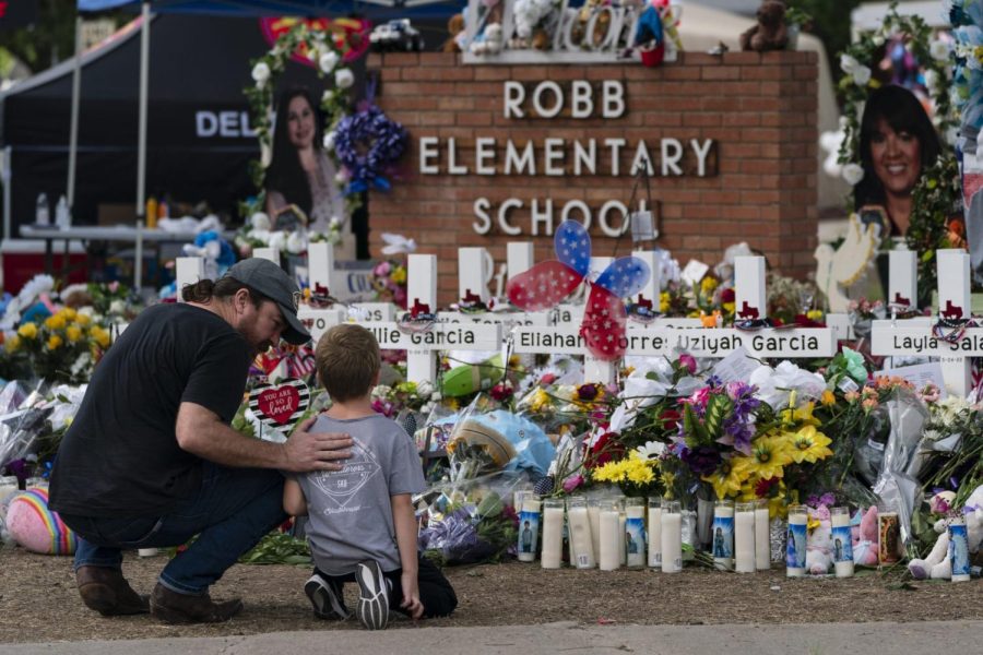 A man and a boy visit a memorial at Robb Elementary School in Uvalde, Texas Sunday, May 29, 2022, to pay their respects for the victims killed in a school shooting. (AP Photo/Jae C. Hong)