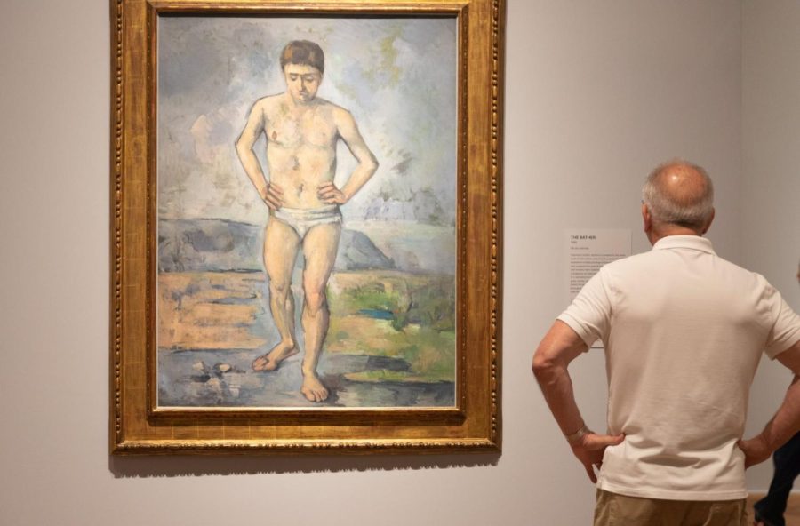 A man reads the description of The Bather, which Cezanne painted in 1885.