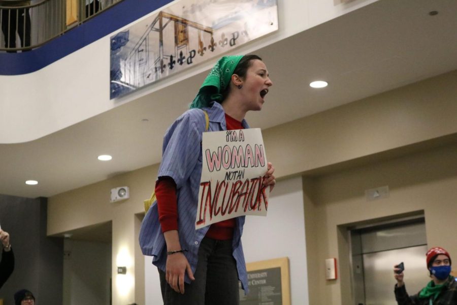 A student screams what their sign reads while standing on a table.