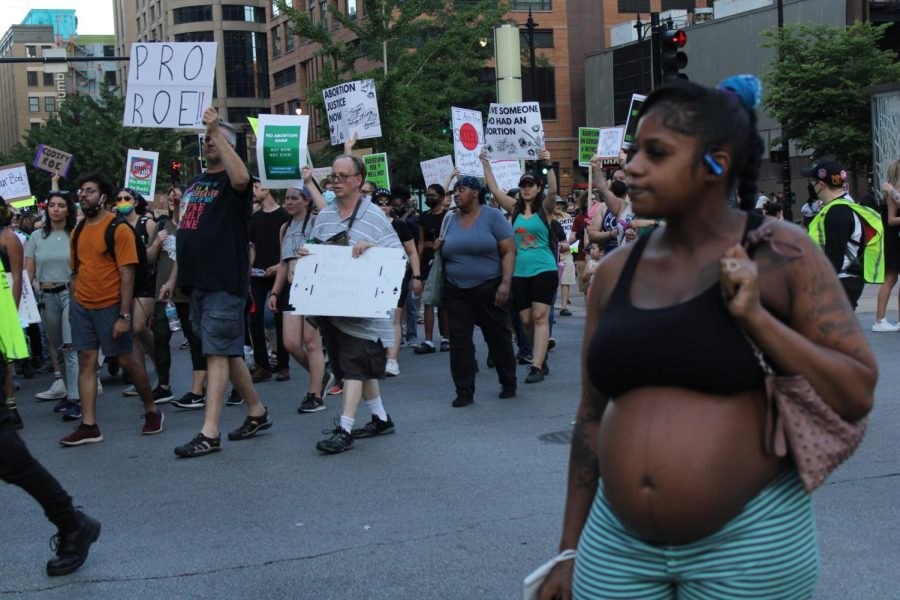 Sade Elicia Washington, una madre soltera embarazada, observa a los manifestantes marchar frente a su parada de autobús y guarda un momento de silencio.