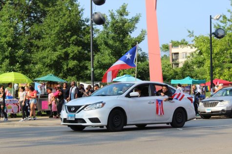 Los estadounidenses puertorriqueños ondean sus banderas con alegria mientras conducen por la calle.