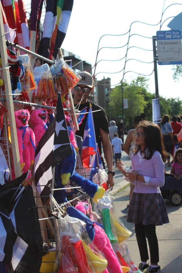 Un vendedor ambulante le muestra a una niña su variedad de banderas, juguetes y recuerdos.