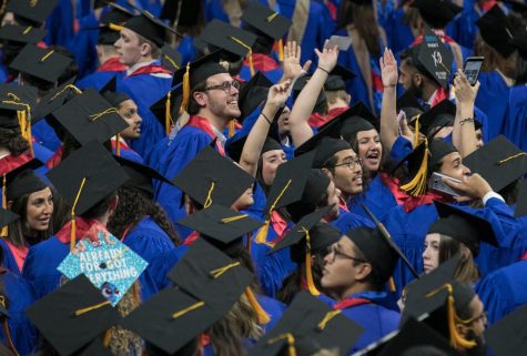 Driehaus College of Business graduates wave to friends and family members inside Wintrust Arena as they take to the floor for their commencement ceremony.