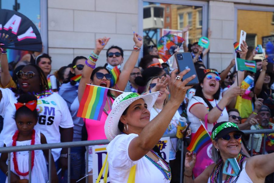A+parade+attendee+holding+up+their+phone+for+a+selfie+with+the+crowd+at+Chicagos+Pride+Parade.