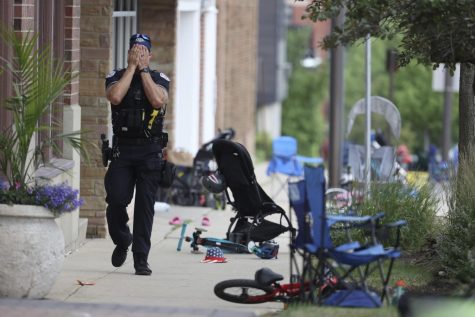A Lake County police officer walks down Central Ave in Highland Park, Ill. on Monday, July 4, 2022, after a shooter fired on the northern suburbs Fourth of July parade