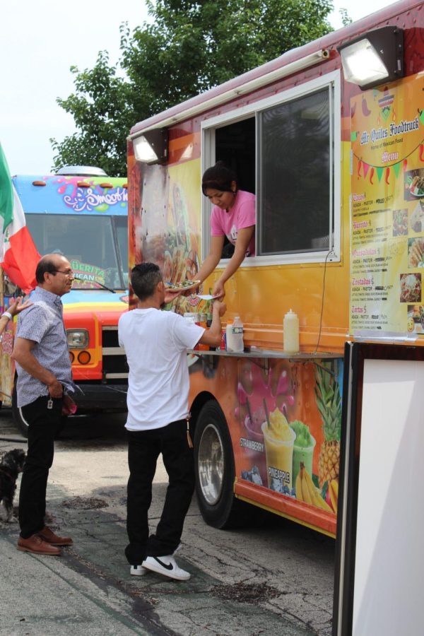 Una empleada de Mr. Quiles, un camión de comida mexicana, le da tacos a un visitante.