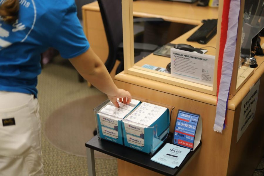 A student worker grabs one of the free rapid tests that is offered in the DePaul Health Promotion & Wellness (HPW) Office. T