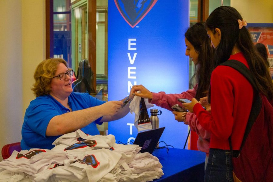 Courtney James, director of the Office of Student Involvement (OSI), hands a DePaul towel to students who registered for an event in the Loop.