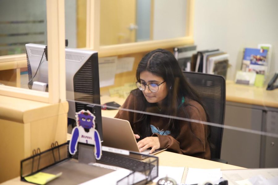 A student works on their homework while working a front desk job at the Division of Student Affairs in the Loop campus.