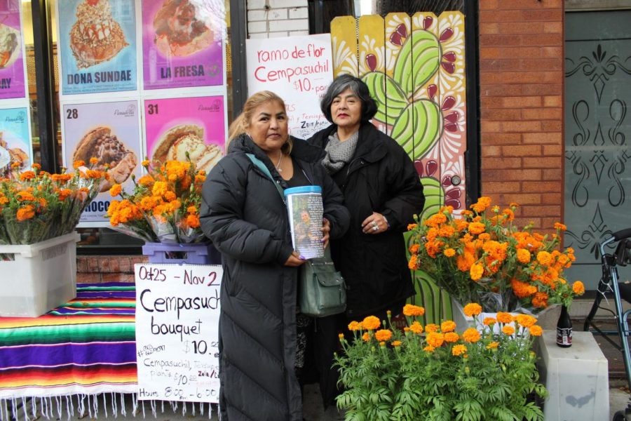 Rocio Olea (left) and Maria Guadalupe Olea (right) stand in front of Panaderia Nuevo Leon in Pilsen selling cempasúchil flowers.