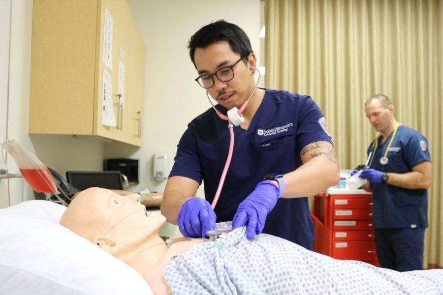 Mark Comia, a graduate assistant at DePaul's School of Nursing, listens to the heartbeat of a mannequin through a stethoscope to practice for his clinicals.