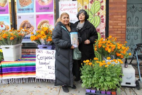 Rocio Olea a la izquierda y Maria Guadalupe Olea a la derecha paradas en frente de Panaderia Nuevo Leon en Pilsen vendiendo flores de cempasúchil.