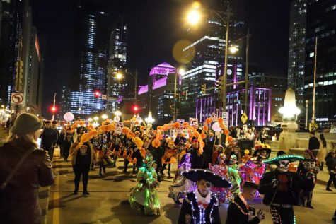 Los participantes del Arts in the Dark Halloween parade caminan por la calle State. 