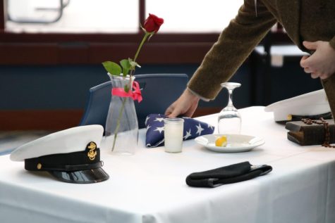 Turman places the folded flag down onto the table for the missing man, paying tribute to those who are captured or labeled as missing during their service.