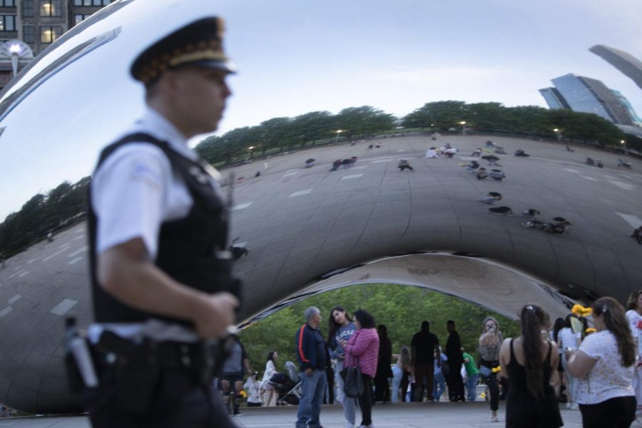A Chicago Police Officer walks by the Bean in Millenium Park Thursday afternoon as visitors take photos near the attraction.