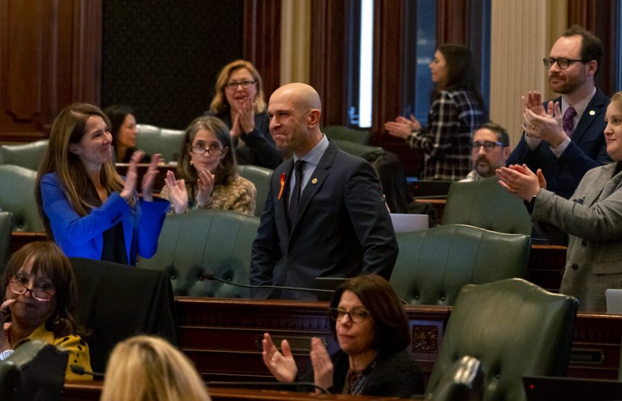 Colleagues applaud state Rep. Bob Morgan after the passage of a gun bill banning assault weapons and high capacity magazines Tuesday, Jan. 10, 2023, at the Illinois State Capitol in Springfield, Ill. Morgan, a sponsor of the bill, was present at the Highland Park mass shooting on July 4, 2022. (Brian Cassella/Chicago Tribune via AP)