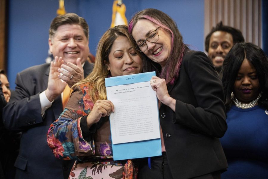 Caption: State Sen. Celina Villanueva (left) and state Rep. Kelly Cassidy (right) hold the signed House Bill 4664 after Gov. J.B. Pritzker signed it into Illinois law.