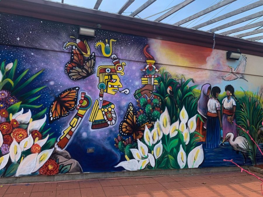 El Dios de Maíz rodeado por mariposas monarcas y mujeres indígenas pintados en un muro afuera de la Taquería El Mesón.
