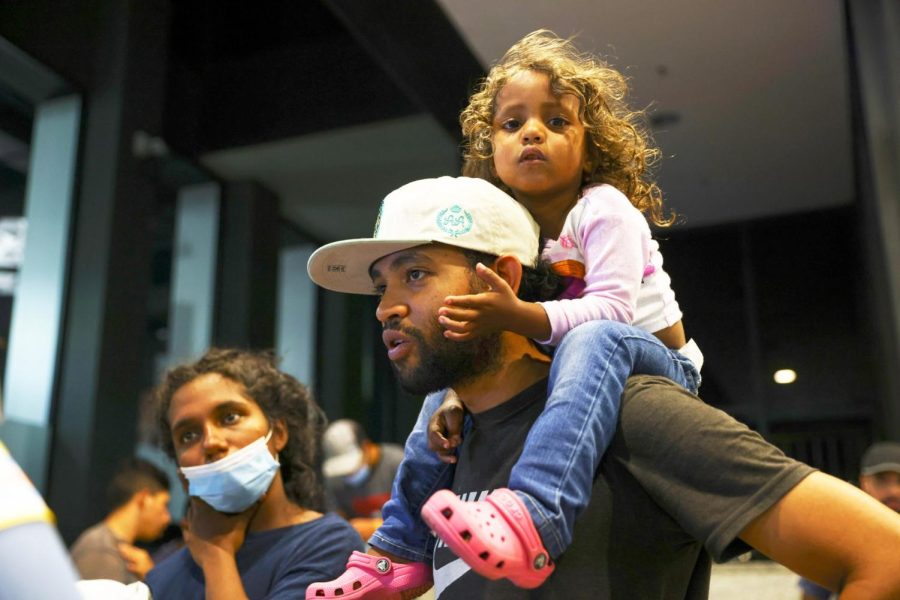 Cataleya sits atop her father, Elier as he speaks to a police officer while other migrants wait for a bus to take them to a refugee center outside Union Station in Chicago on Aug. 31, 2022.