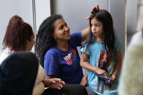 (Center) Karen Malave, an immigrant from Venezuela, smiles as she fixes her daughter Avril Brandellis hair. They and other families are taking shelter in a Chicago Police Department station.