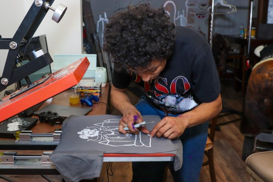 Gerardo Arroyo Carrillo usando una prensa térmica para diseñar sus prendas de vestir.