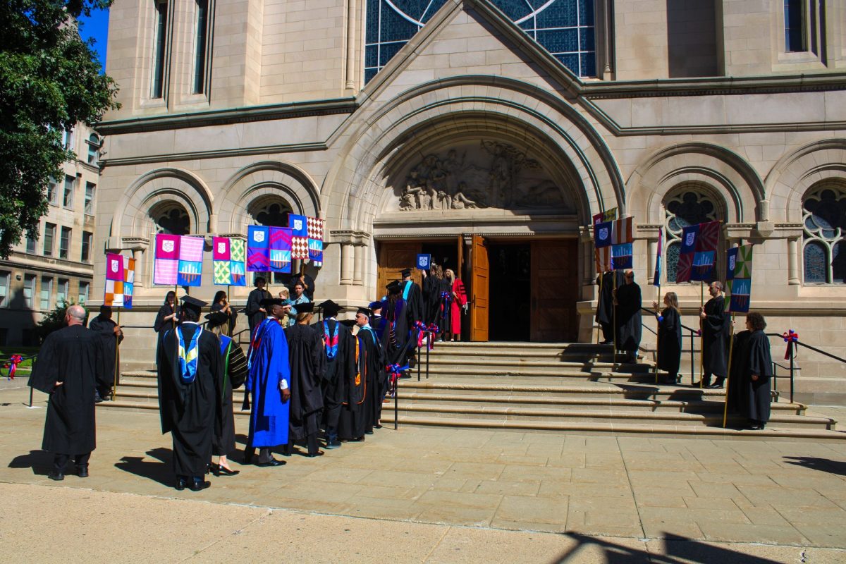 University administrators, faculty and staff walk into the St. Vincent de Paul church in regalia.