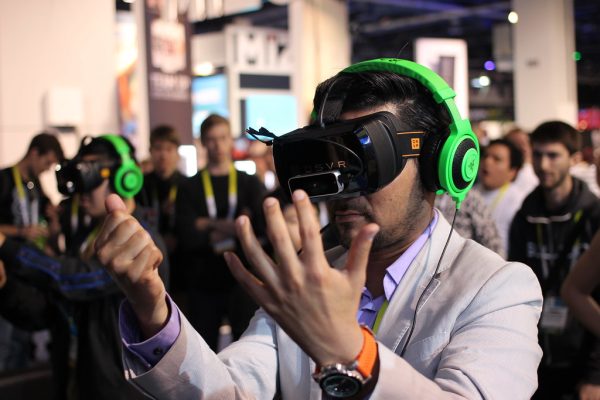 A man tests a virtual reality headset among a crowd of spectators.