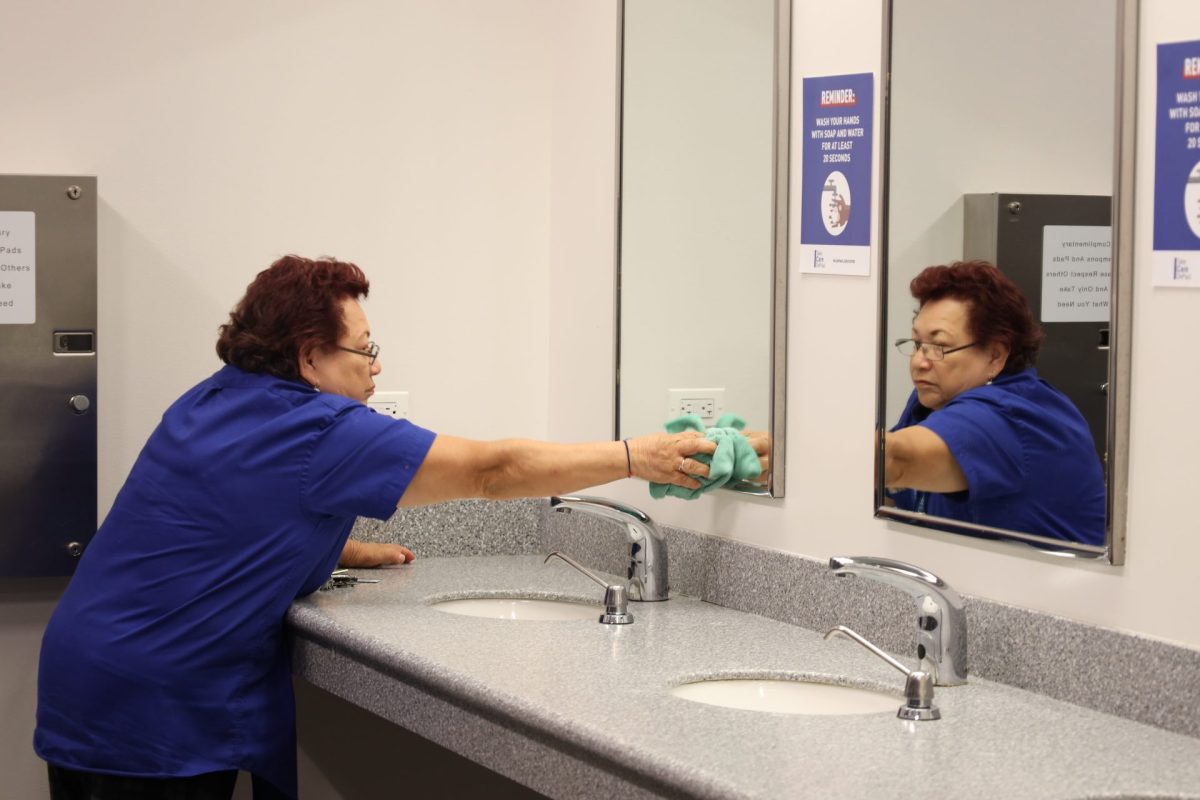 Maria Arvizo, a custodian at DePaul, cleans a mirror in the womens bathroom at OConnell Hall on Oct. 10. Arvizo is known as Doña Maria among students and staff. 
