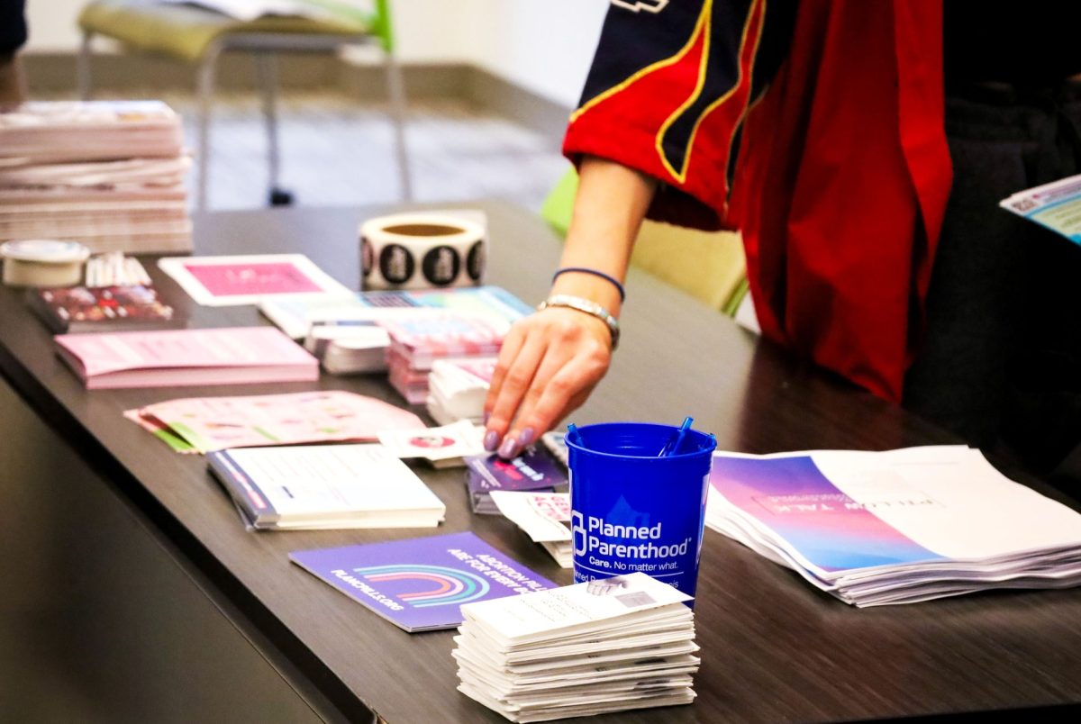 A student grabs one of the free stickers available to attendees. The meeting was held in Arts and Letters on Wednesday evening.