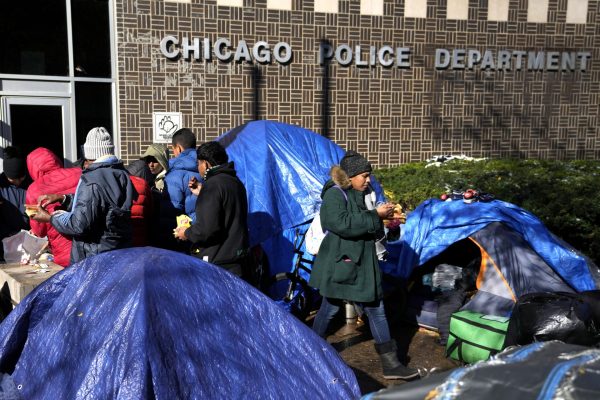 Hot dogs are served to migrants, Wednesday, Nov. 1, 2023, outside a Northside police station where they live in a small tent community in Chicago. 