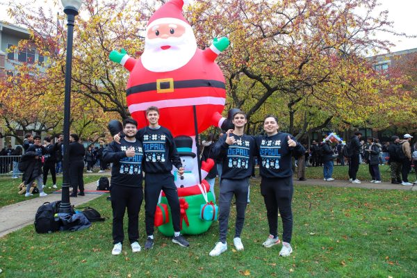 Eric Guzman, Jason Gould, Francesco Pollina and Nicholas Prusa pose by a Santa inflatable at the Ugly Sweater Party on Wednesday, Nov. 8, 2023, on the DePaul Lincoln Park Campus. The friends were among hundreds of students who stood in line to receive the sweaters at the annual event.
