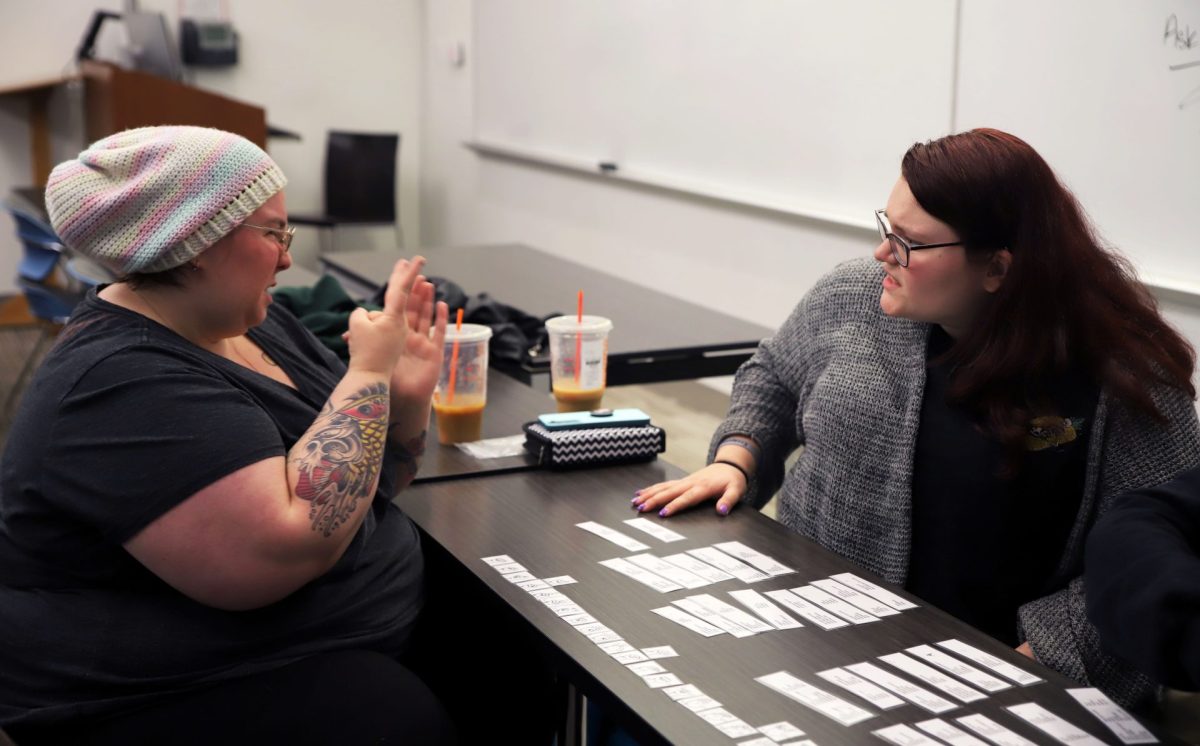 ASL Club vice president Kes Eary, left, and president Sarah Hau, right, interact about the game they’re playing, completely in Sign Language during a meeting on Nov. 9, 2023. During meetings, a large portion of the time is “voices off,” meaning everyone has to communicate only in Sign Language.