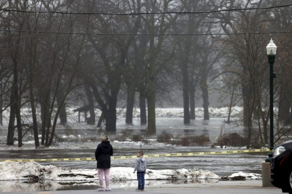 Nicole Bogash and her son Ryder, 5, look on as the Kankakee River floods the nearby banks and portions the of downtown area, affecting several business across the river, Friday, Jan. 26, 2024, in Wilmington, Il. 