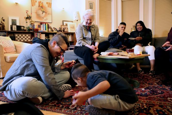 Kelly Kessler, DePaul Media and Cinema studies professor, and Pablo Mota play cards on the floor of the Kessler-Flauto family’s living room before dinner on Nov. 5. Cissy Hubbard, who is Flautos mother, Emilio Mota and Albani Rivero laugh in the background as they watch the two play “War.” 