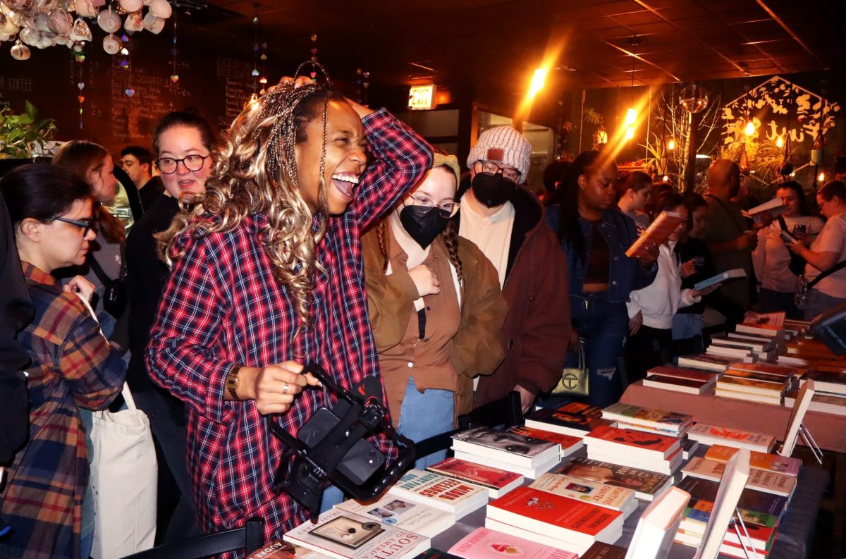 A book fair patron laughs while browsing a selection of books on Tuesday, Feb. 27, 2024, at First Sip Cafe in Chicago. Crowds of people lined up to see the books during the adult book fair co-hosted by First Sip and Call and Response Books.