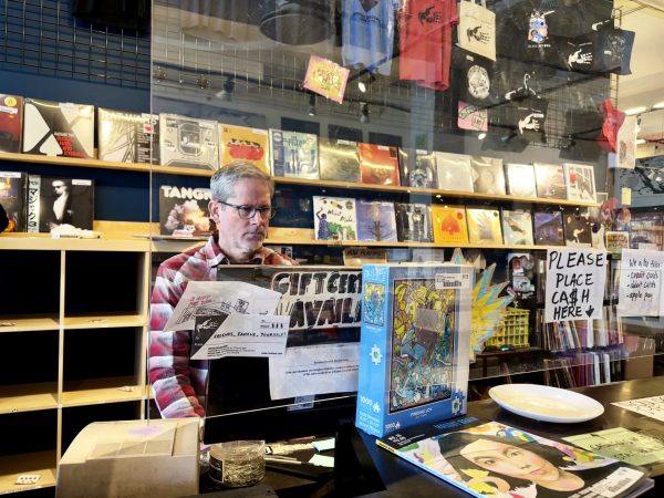 Kip McCabe, a manager at Reckless Records, stands behind the counter at the record store on Thursday, Feb. 29, 2024. McCabe says it is gratifying to see a younger generation become interested in physical media.