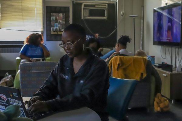 Ava Francis types away in the Black Cultural Center as students relax in the space behind her on Thursday, Feb. 22, 2024. Hired in August 2022, this will be her second year in the role.