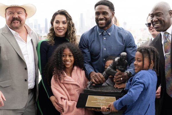 Former USC football player Reggie Bush poses with his attorneys, left, Levi McCathern and Ben Crump, right, along with his and family and his Heisman trophy during a news conference at the Los Angeles Memorial Coliseum, Thursday, April, 25, 2024, in Los Angeles.