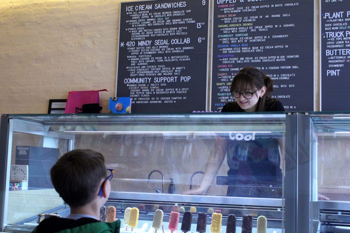DePaul+sophomore+Greta+Atilano+helps+a+young+Pretty+Cool+Ice+Cream+customer+pick+out+an+ice+cream+flavor+on+Friday%2C+April+19%2C+2024.+Its+the+perfect+job+for+a+college+student%2C%E2%80%9D+Atilano+said.+%E2%80%9CI+started+working+here+my+freshman+year.+I+always+try+to+work+for+small+businesses+%5Band%5D+putting+back+into+the+community.+Of+course%2C+interacting+with+kids+is+a+lot+of+fun+too.