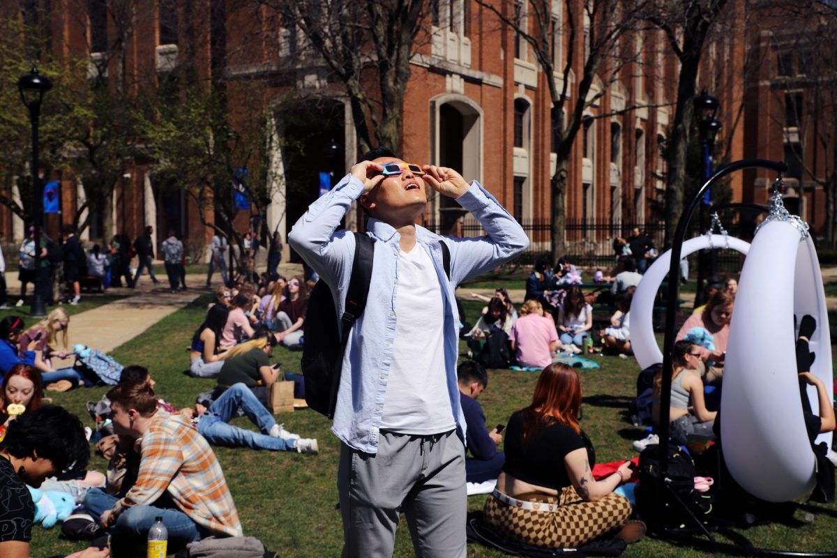 Benedict Lu stares at the eclipse through his glasses on Monday, April 8, 2024, in the quad. The peak for the eclipse in Chicago hit at 2:07 p.m.