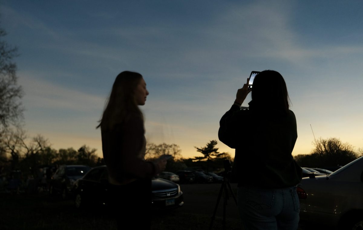 Elizabeth Miller and Sophie Young take a photo of the sun on their phone as they experience totality during the solar eclipse from Fairbanks Park in Terre Haute, IN, on Monday, April 8, 2024. For three minutes, the park was cloaked in darkness as the moon blocked the sun.