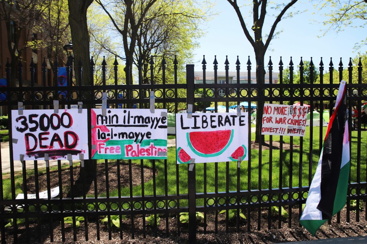 Signs hang on the Quad gates on DePaul’s Lincoln Park campus. DePaul is the latest university to form an encampment, urging the administration to “divest from Israel”. 