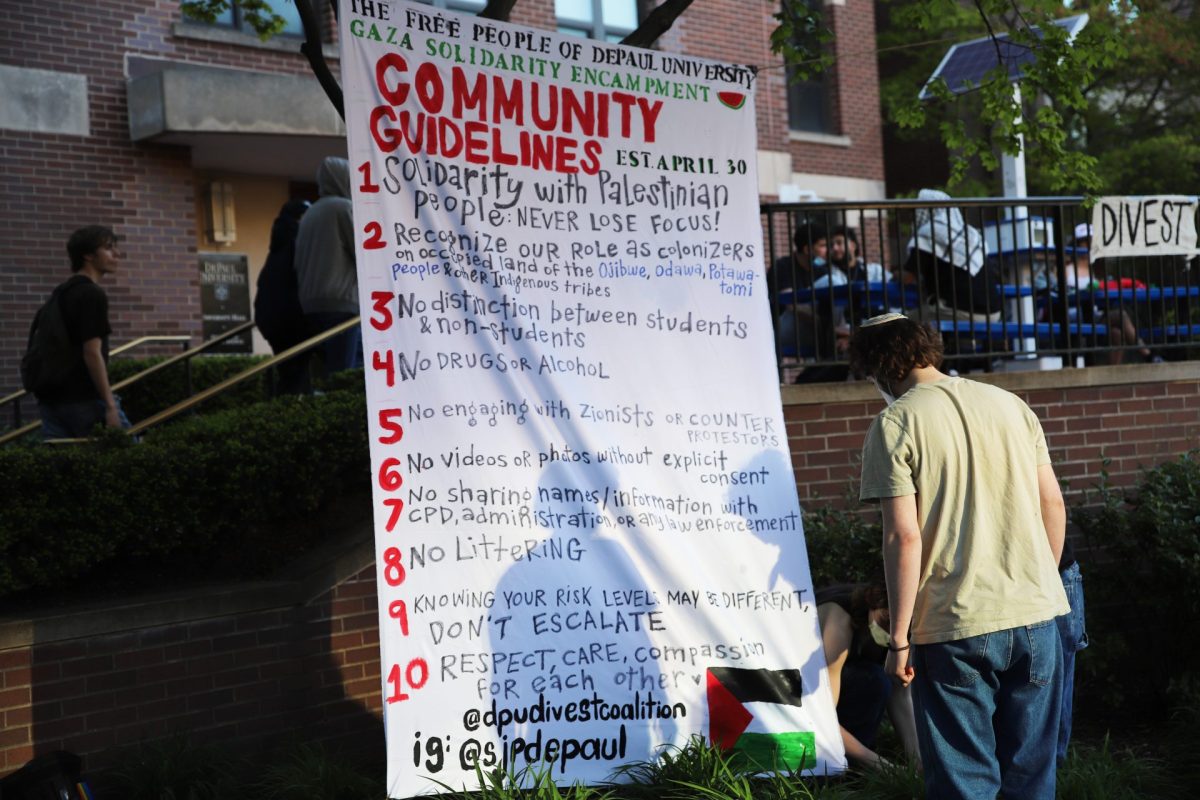 Demonstrators at DePauls encampment on the Quad, hang a sign that reads Community Guidelines, on April 30 at 6:15. The list of rules for the encampment were also noted in the 2 p.m. live update.  