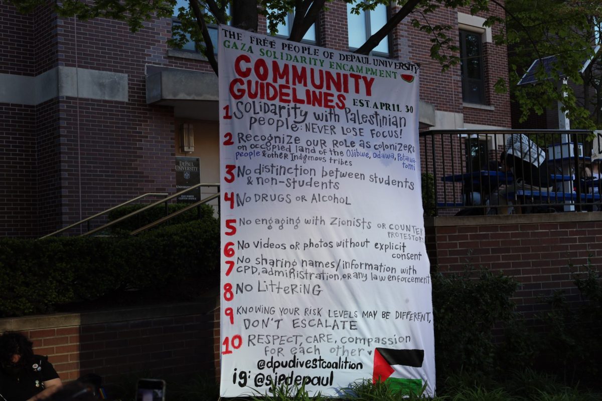 Estudiantes manifestantes en el campamento de DePaul en el patio central cuelgan un letrero con sus pautas comunitarias el 30 de abril de 2024. El letrero fue pintado por los estudiantes manifestantes.
