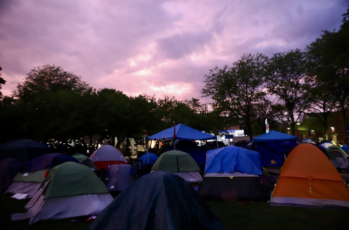 As+the+sun+sets+on+the+encampment+on+DePaul%E2%80%99s+Quad+a+thunderstorm+passed+through%2C+as+protestors+took+shelter+in+tents+and+the+Richardson+Library.+As+the+rain+cleared%2C+protestors+walk+around+the+Quad.